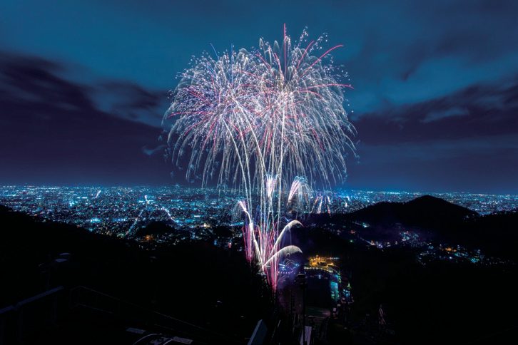 冬の夜空に上がる花火と札幌の夜景